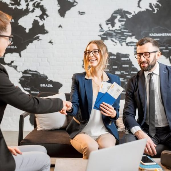 young-businesscouple-choosing-trip-with-agent-sitting-travel-agency-office-with-world-map-background_506452-3029